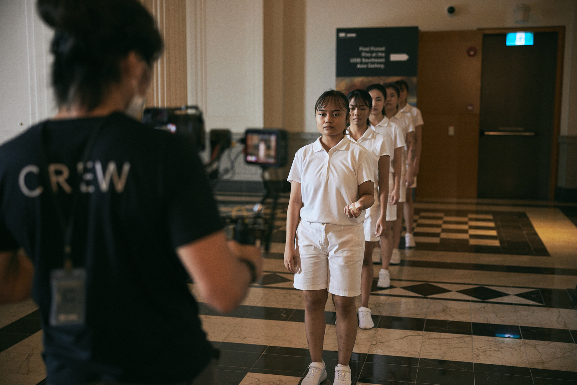 Dancers stand in a line as crew set up the film shot.