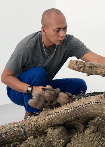 Zul Mahmod kneels by an artwork